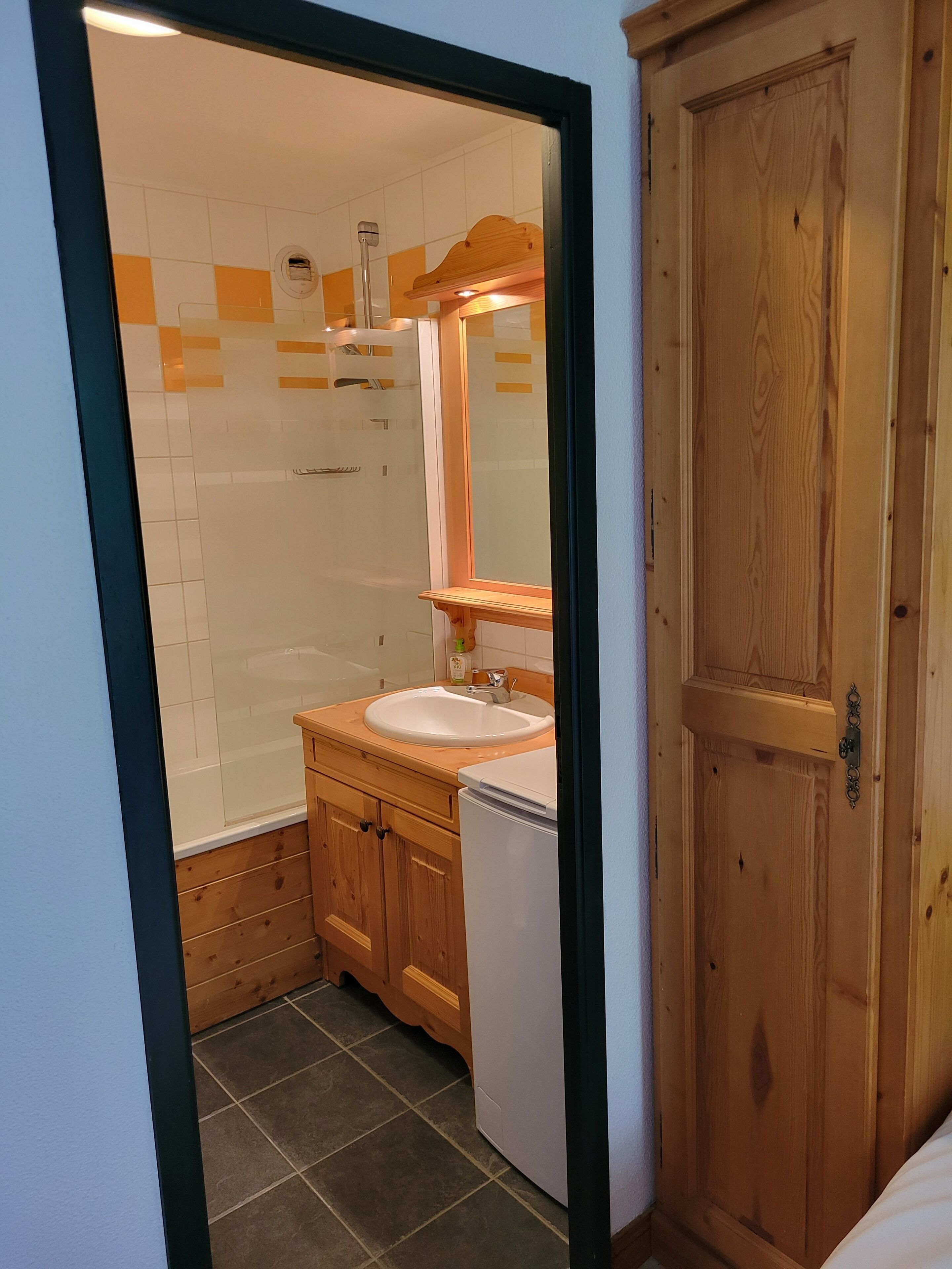 A bathroom with a shower, sink, and wooden cabinets.