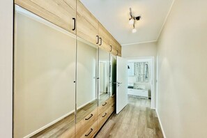 Ein Flur mit einem Holzschrank, einem Spiegel und einem weißen Badezimmer im Hintergrund.
