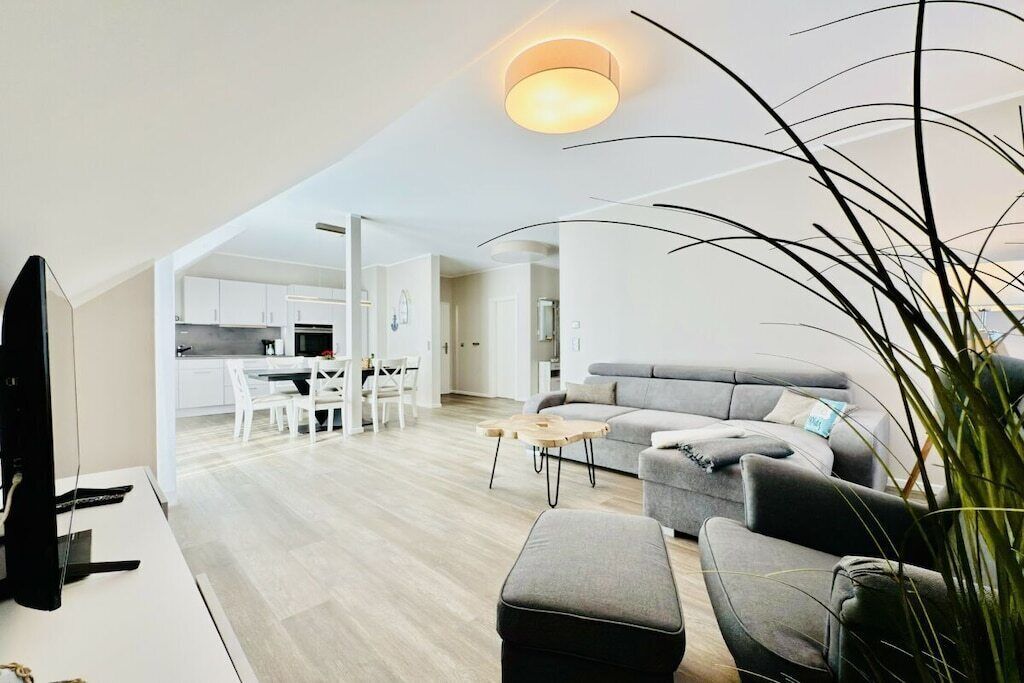 A modern living room with a grey sofa, a coffee table, and a TV on a stand.