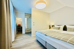 A hotel room with a bed, bedside table, and a view of a hallway.