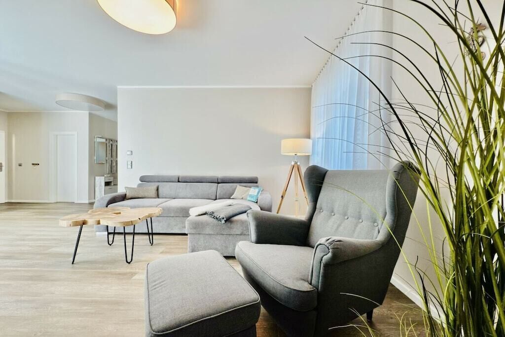 A modern living room with a grey sofa, a matching armchair, a wooden coffee table, and a floor lamp.