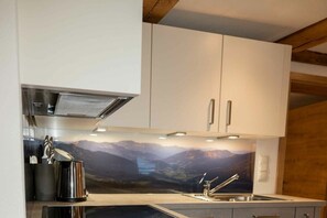 Een moderne keuken met witte kastjes, roestvrijstalen apparatuur en een prachtig uitzicht op de bergen.