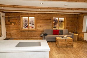 A wooden interior with a sofa, a coffee table, and two windows with snowy scenes. - Sorgschrofen- Lärchenhof Jungholz (Jungholz)