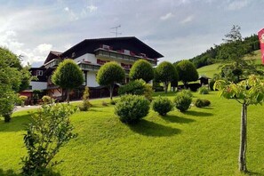 A hotel with multiple floors, a well-maintained lawn, and a variety of trees. - Sorgschrofen- Lärchenhof Jungholz (Jungholz)