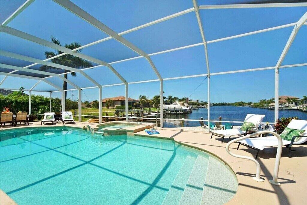 A pool area with a clear view of the water, surrounded by lounge chairs and a covered structure.