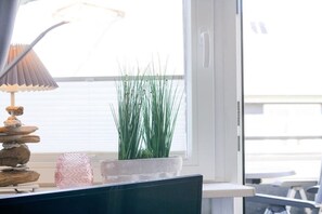 A room with a computer desk, a lamp, a potted plant, and a window with blinds. - Holiday apartment in Sylt with 2 bedrooms (Wenningstedt)