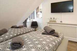 A bedroom with two beds, a TV, and a radiator. - Holiday apartment in Sylt with 2 bedrooms (Wenningstedt)