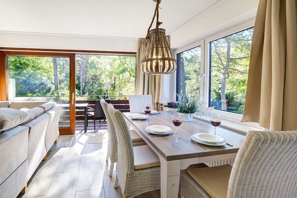 A dining area with a wooden table, chairs, and a hanging light fixture.