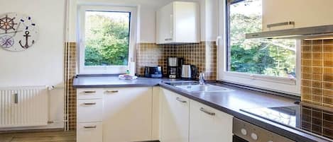 Una cocina moderna con armarios blancos, horno empotrado y ventana que proporciona luz natural.