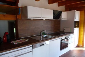 A kitchen with white cabinets, a stainless steel sink, and a built-in oven. - Holiday home with 1 bedroom (Otterndorf)