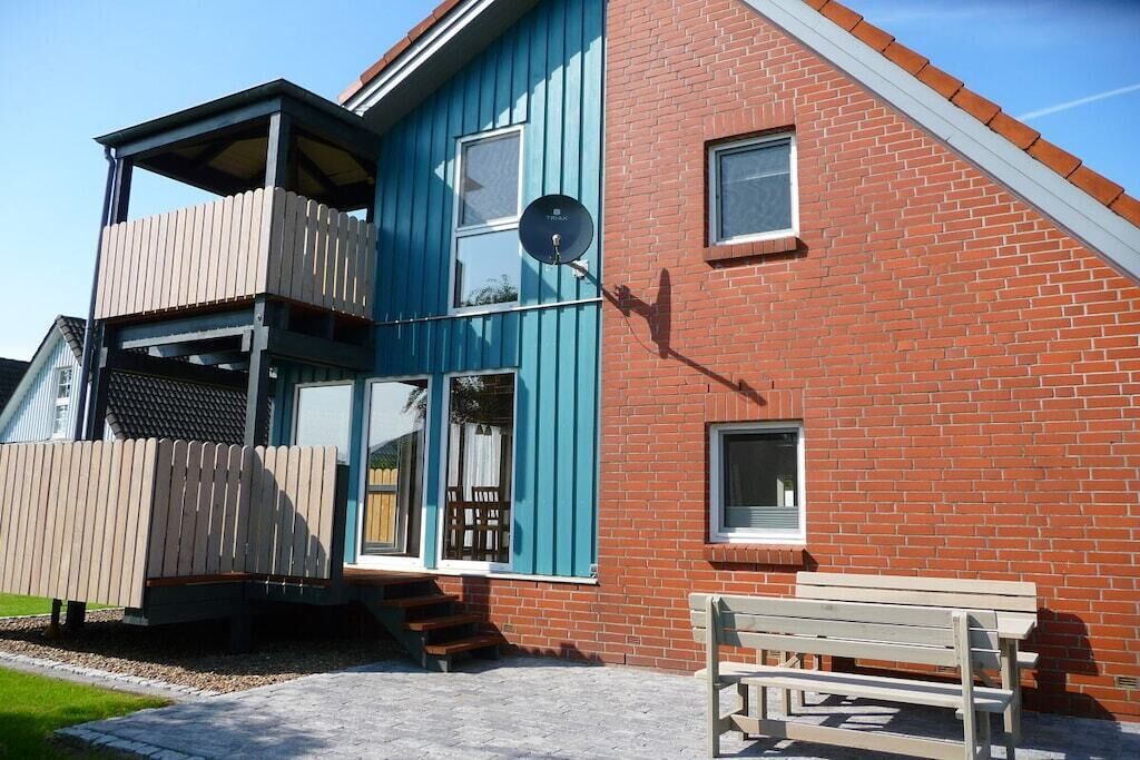 Un bâtiment à deux étages doté d’un balcon, d’une antenne parabolique et d’un banc à l’extérieur.