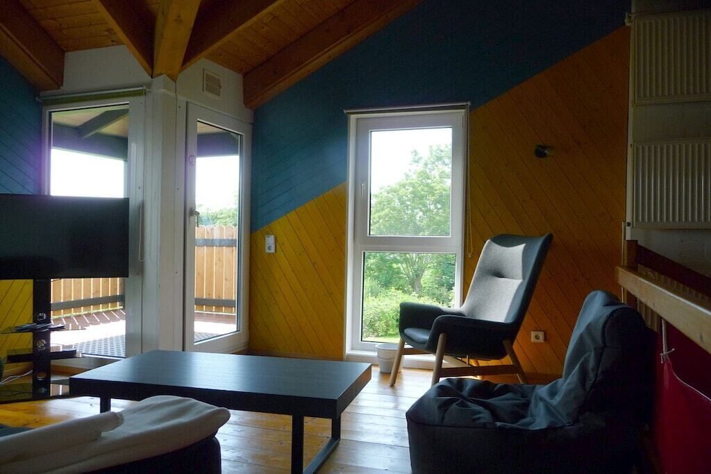 Una habitación con una mesa, una silla, un banco y un ventanal grande.