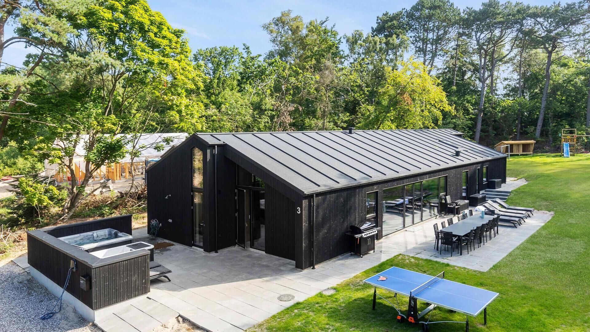 A modern outdoor structure with a patio area, seating, and a ping pong table.