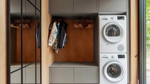 A compact laundry room with two stacked washing machines and a wooden wardrobe with hanging space. - VillaVilla 994 - Øster Hurup, Østjylland (Hadsund)