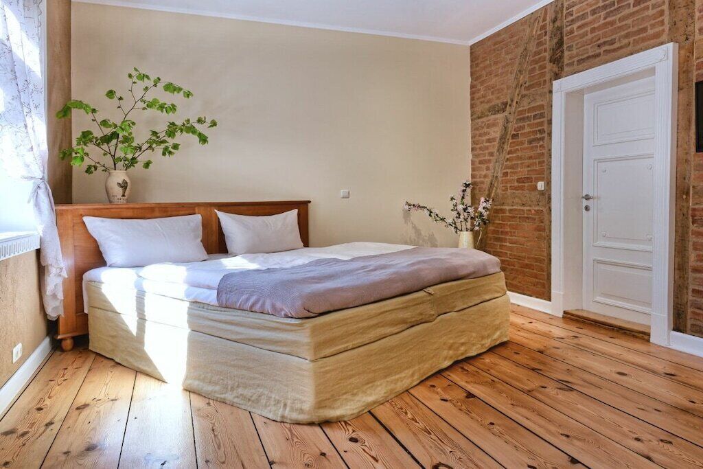 Ein Schlafzimmer mit einem hölzernen Bett, einer Backsteinwand und einer weißen Tür.