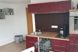 Een kleine keuken met een vaatwasser, een koffiezetapparaat en een magnetron.