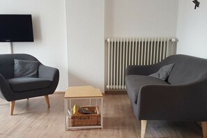 Een woonkamer met twee banken, een televisie en een radiator.