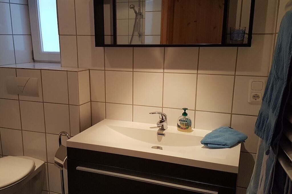 Een badkamer met een wit wastafel, een spiegel en een raam.