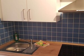 A kitchen with a sink, a stove, and cabinets. - Holiday apartment with 1 bedroom (Dornumersiel)
