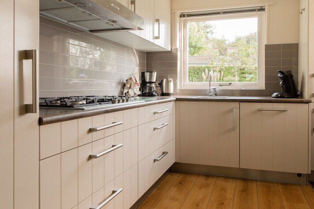 Una cocina moderna con estufa a gas, cafetera y ventana con vista al exterior.
