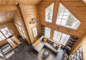 A cabin interior with a dining area, a sofa set, and large windows. - Ihtinginrinne | Peaceful 2BR Log Villa by the Lake (Ruka)