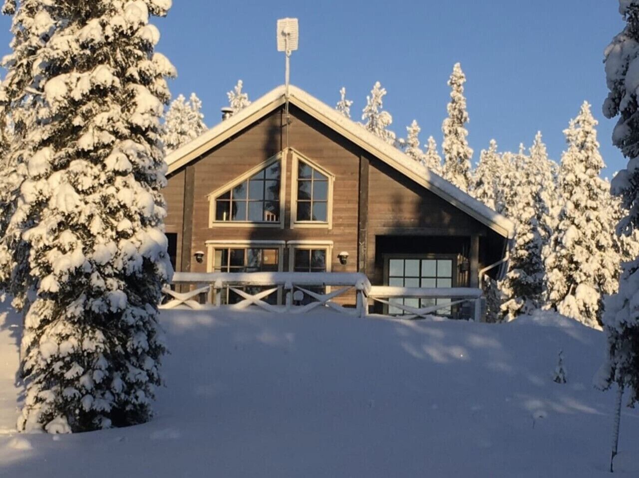 Una baita di legno con un ampio garage, circondata da alberi innevati.
