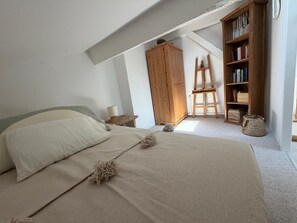 Ein Schlafzimmer mit einem Bett, einem Holzschrank, einem Bücherregal und einer Leiter.