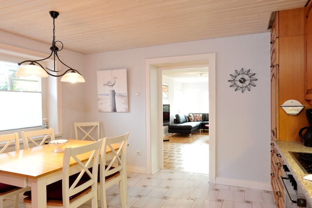 En matplats med ett träbord och stolar, en kristallkrona och en tavla på väggen.