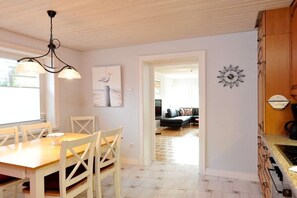 A dining area with a wooden table and chairs, a chandelier, and a painting on the wall. - Grutte Budde in the house Dünenblick (Westerland)