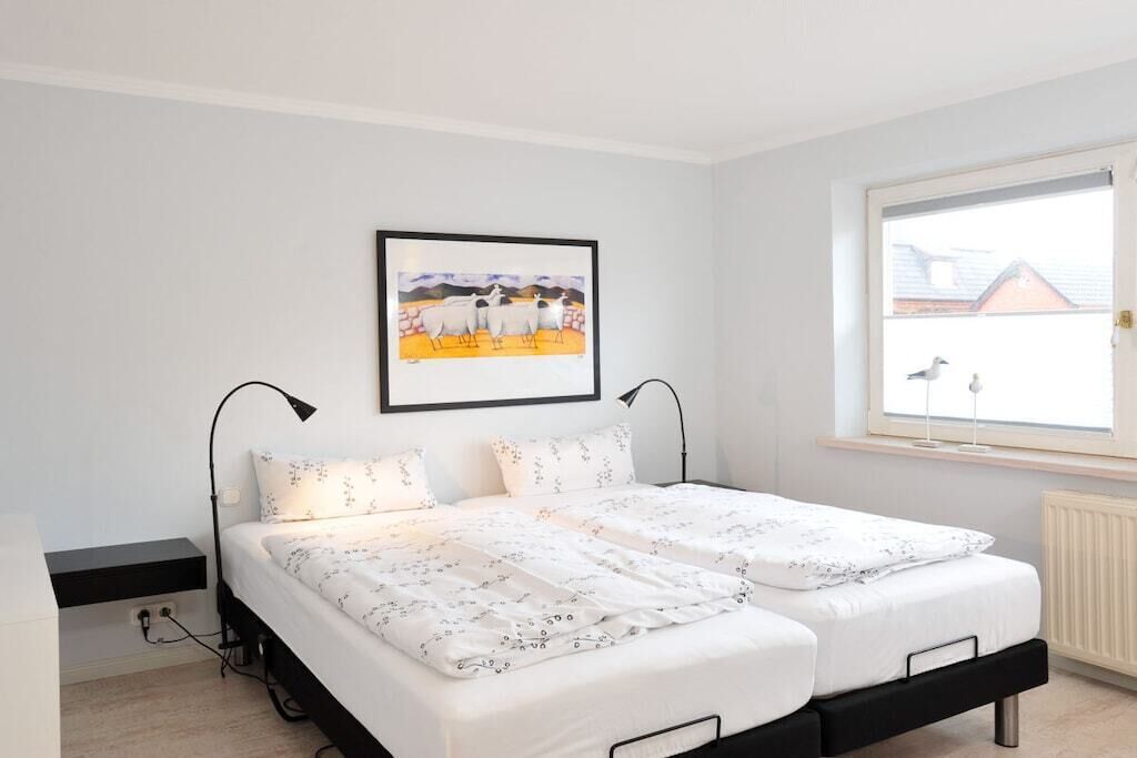 A bedroom with a bed, a window, and a wall-mounted picture.