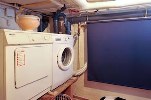 A laundry area with a white Miele washing machine and dryer, a blue cabinet, and visible plumbing. - Grutte Budde in the house Dünenblick (Westerland)