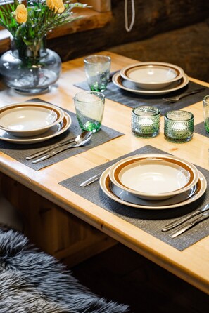 Een gedekte eettafel met borden, glazen en bestek, wat wijst op een bereid diner.