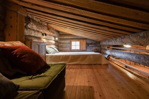 Ein gemütliches Schlafzimmer in einer Blockhütte mit einem Bett, einer Bank und einem Fenster.