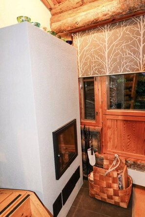 A room with a fireplace, wooden cabinets, and a window with a tree pattern. - Rukkanen | Cozy 1BR Apt |  Fireplace & Terrace (Ruka)