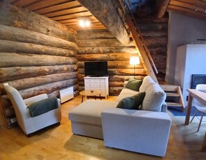 A log cabin interior with a sofa set, a television, and a small table.