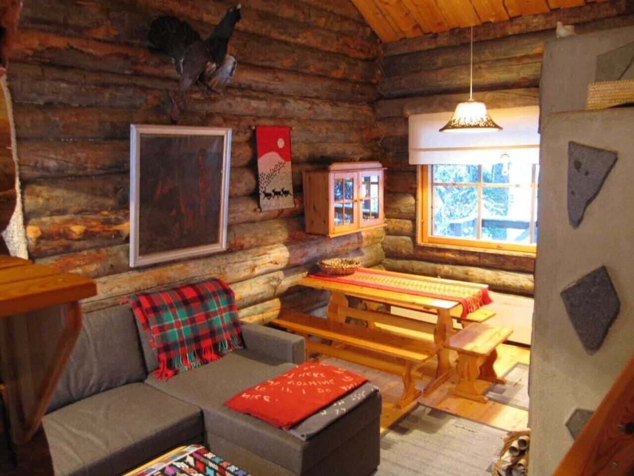 Ein gemütliches Blockhaus-Interieur mit einer Couch, einer Bank, einem Tisch und einem Fenster.