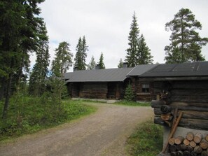 Ein rustikales Holzhäuschen, das von einem Kiesweg erreichbar ist, umgeben von dichtem Wald.