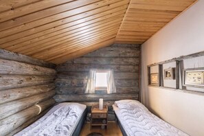 Eine Hütte mit zwei Betten, einem Vorhangfenster und einer Wand mit gerahmten Bildern.
