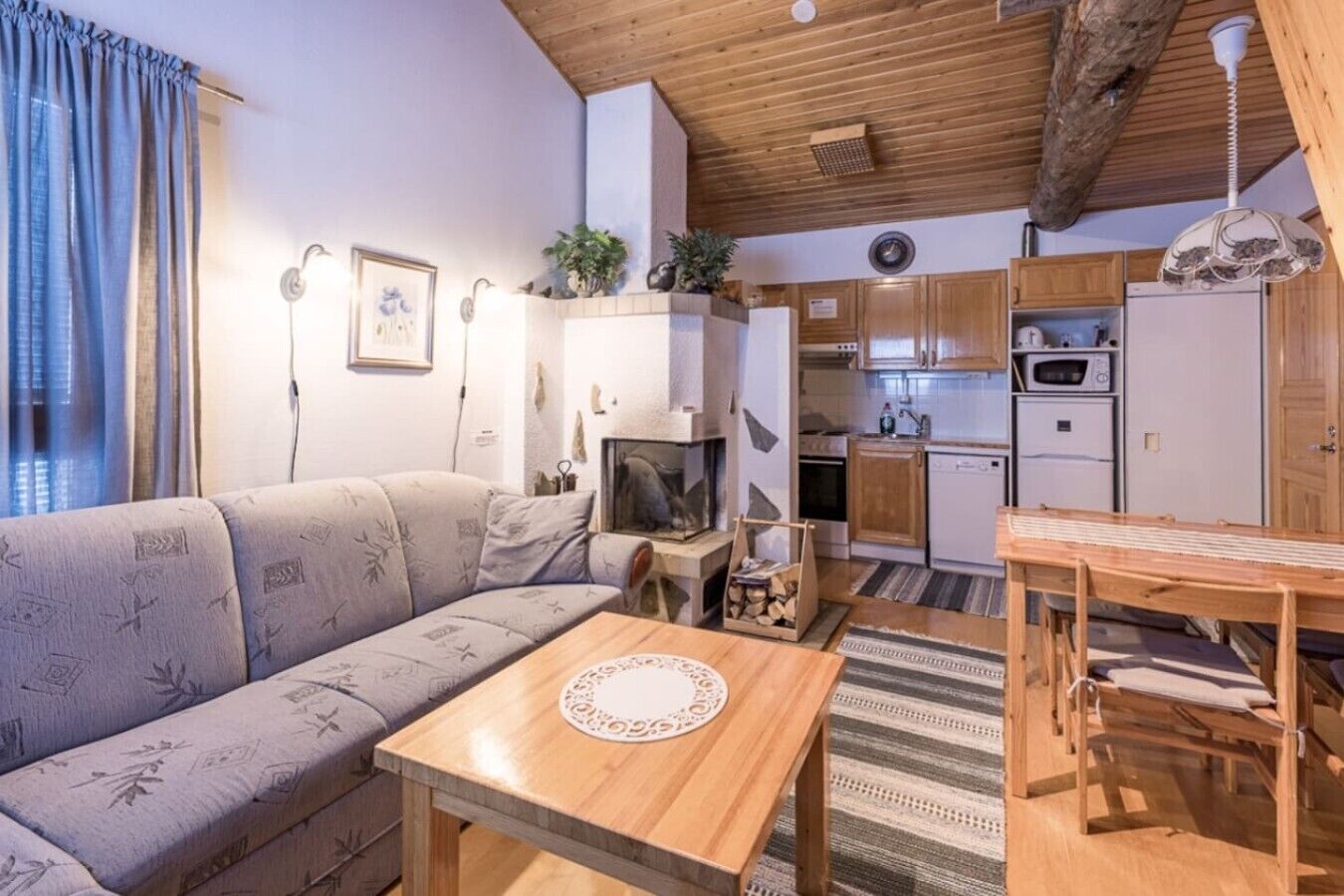 Un salon confortable avec un canapé, une table en bois et un coin cuisine équipé de placards et d’appareils électroménagers.