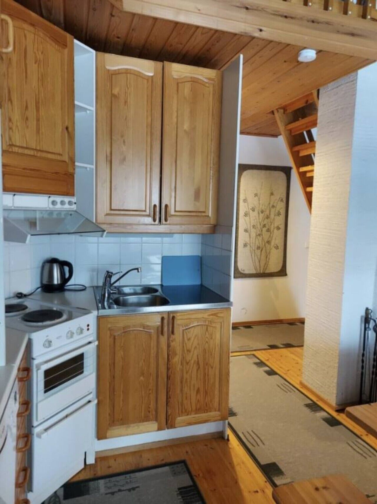 A kitchen with wooden cabinets, a stove, and a sink.