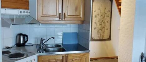 A kitchen with wooden cabinets, a stove, and a sink.