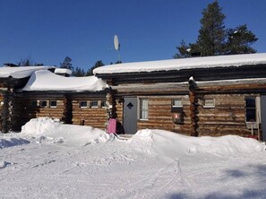 Une cabane en rondins dont le toit est recouvert de neige, avec une antenne parabolique.