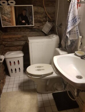 Une petite salle de bain comprenant des toilettes, un lavabo et un lave-linge.