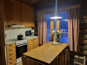 Eine Küche mit Holzausstattung, einem Herd, einer Kaffeemaschine und einer Vase mit Blumen auf der Arbeitsfläche.