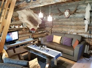 L’intérieur d’une cabane en rondins, avec un canapé, un téléviseur et une table agrémentée d’objets décoratifs.