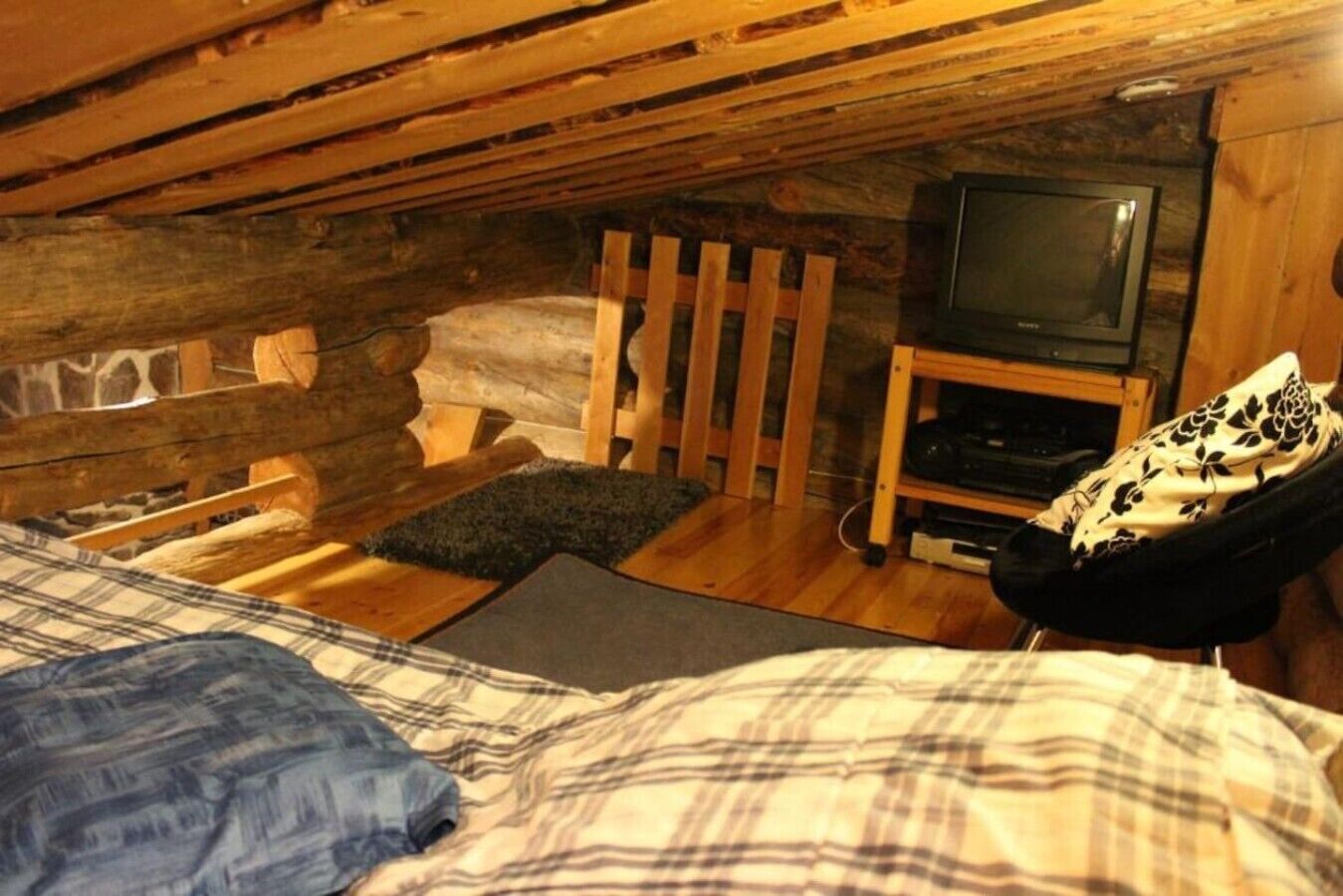 Une chambre confortable située dans les combles, avec un lit, un petit canapé, une télévision et une cheminée.