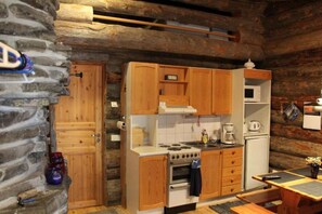A rustic kitchen with wooden cabinets, a stove, and a microwave.