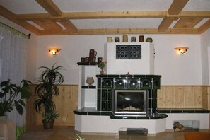 A living room with a fireplace, wooden beams, and wall-mounted lighting. - Holiday home with 2 bedrooms (Muldenhammer\/OT Hammerbrücke)