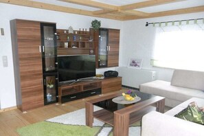 Un salon équipé d’un téléviseur à écran plat, de meubles en bois, d’un canapé et d’une table basse.