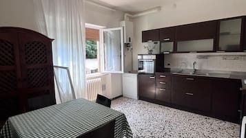 Una cucina compatta con mobili scuri, un forno a microonde e un lavandino.